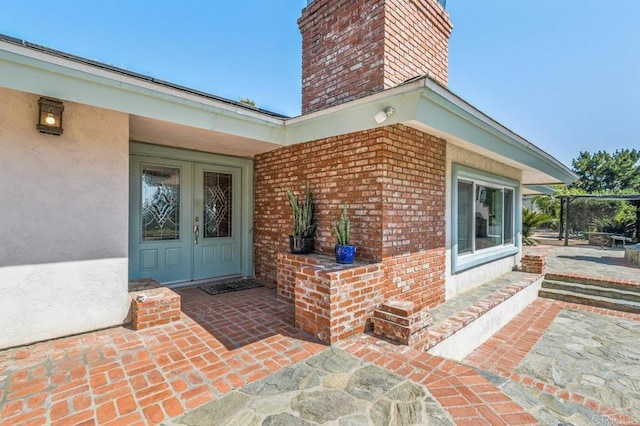 1923 Hidden Mesa Rd, El Cajon, CA 92019 - property entrance with a chimney, brick siding, french doors, and stucco siding