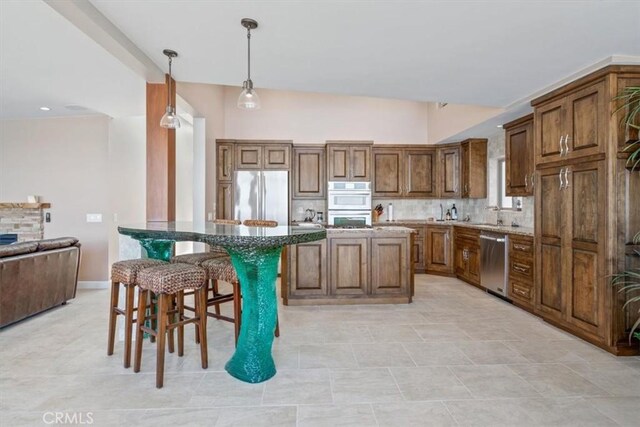 3352 Studio Dr, Cayucos, CA 93430 - kitchen with stainless steel appliances, a kitchen breakfast bar, tasteful backsplash, decorative light fixtures, and stone counters