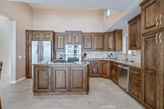 3352 Studio Dr, Cayucos, CA 93430 - kitchen with stainless steel appliances, backsplash, light stone counters, a kitchen island, and baseboards