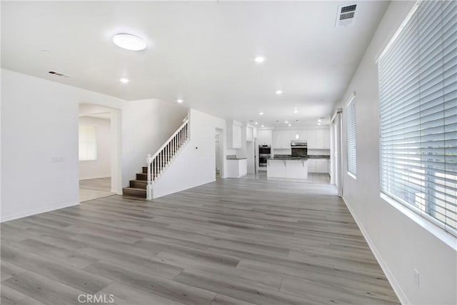 13153 Stanton Dr, Rancho Cucamonga, CA 91739 - unfurnished living room with stairs, recessed lighting, healthy amount of natural light, light wood-style flooring, and baseboards