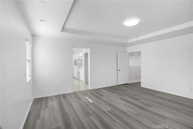 13153 Stanton Dr, Rancho Cucamonga, CA 91739 - unfurnished bedroom with a tray ceiling, wood finished floors, ensuite bath, and baseboards