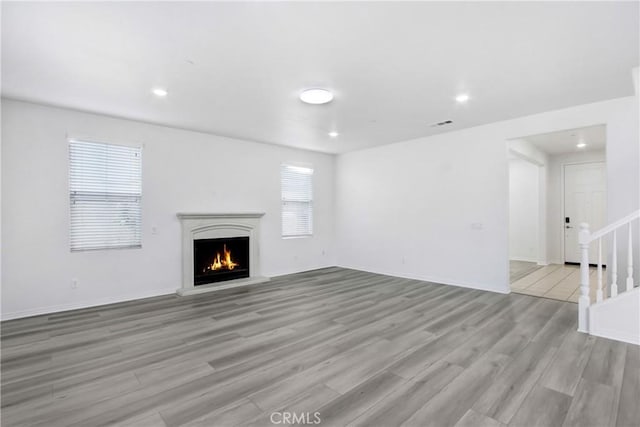 13153 Stanton Dr, Rancho Cucamonga, CA 91739 - unfurnished living room with a lit fireplace, light wood-type flooring, recessed lighting, stairs, and baseboards