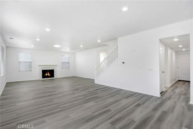 13153 Stanton Dr, Rancho Cucamonga, CA 91739 - unfurnished living room featuring light wood-style flooring, stairs, recessed lighting, a warm lit fireplace, and baseboards
