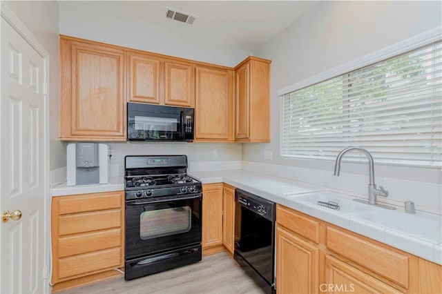 9135 W Rancho Park Cir, Rancho Cucamonga, CA 91730 - kitchen with black appliances, a sink, light brown cabinets, light wood-style flooring, and tile countertops