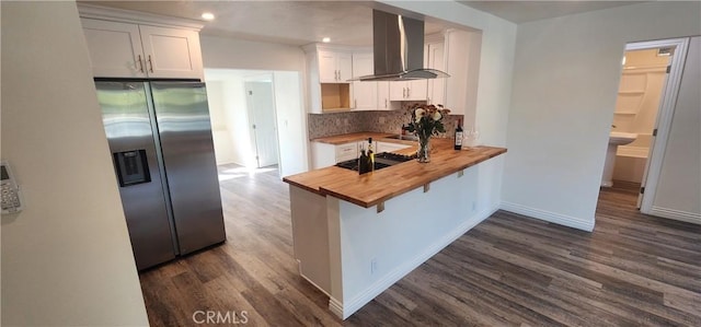 5818 Tyler St, Riverside, CA 92503 - kitchen featuring butcher block counters, wall chimney range hood, stainless steel fridge, dark wood-type flooring, and white cabinetry