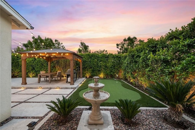 4745 S Mae Way, Ontario, CA 91762 - yard at dusk with a gazebo, an area to practice putting, a patio, and a fenced backyard