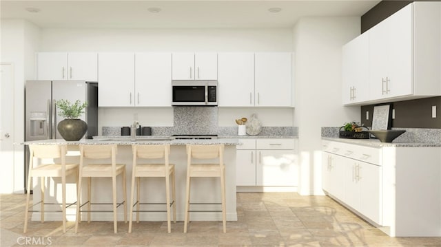 7651 Taylor Ave, Hesperia, CA 92345 - kitchen with stainless steel microwave, a kitchen island, backsplash, white cabinetry, and a kitchen bar