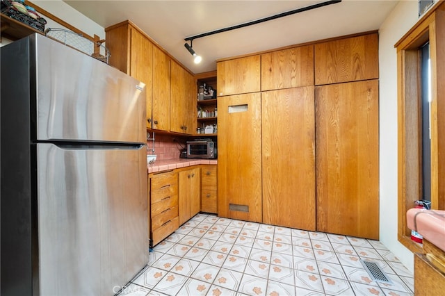 125 W 11th St, Claremont, CA 91711 - kitchen featuring freestanding refrigerator, tile countertops, open shelves, backsplash, and brown cabinetry