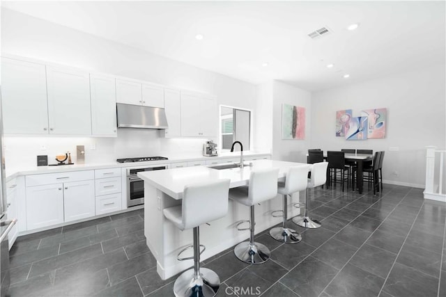 26956 Nature View Pl, Valencia, CA 91355 - kitchen with under cabinet range hood, stainless steel oven, a sink, a breakfast bar area, and white cabinetry