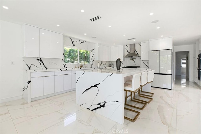 12410 Mclennan Ave, Granada Hills, CA 91344 - kitchen with modern cabinets, wall chimney exhaust hood, light marble finish floors, white cabinets, and recessed lighting