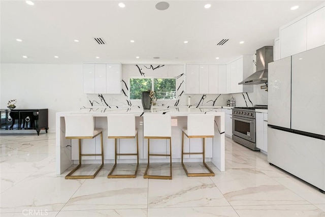 12410 Mclennan Ave, Granada Hills, CA 91344 - kitchen with freestanding refrigerator, high end stainless steel range oven, wall chimney exhaust hood, light marble finish floors, and modern cabinets
