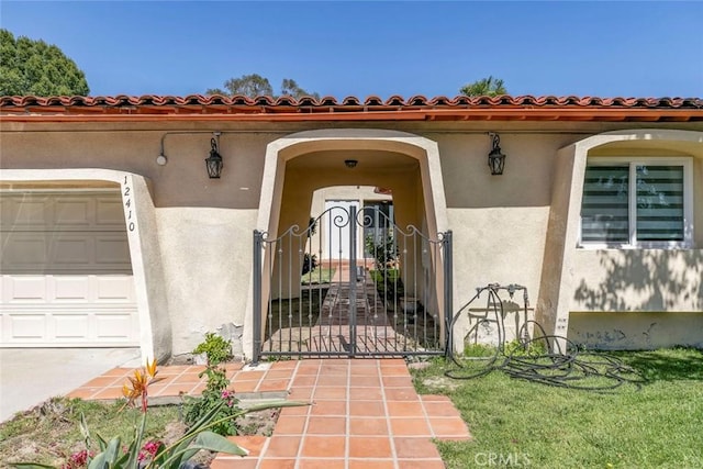 12410 Mclennan Ave, Granada Hills, CA 91344 - view of exterior entry with a garage, stucco siding, and a gate