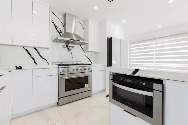 12410 Mclennan Ave, Granada Hills, CA 91344 - kitchen featuring wall chimney exhaust hood, stainless steel appliances, white cabinets, light marble finish flooring, and modern cabinets