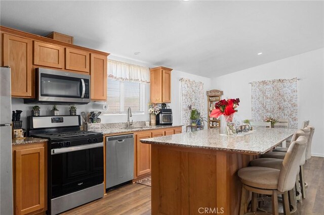 1863 Norwood Dr, Paradise, CA 95969 - kitchen with appliances with stainless steel finishes, a sink, wood finished floors, a kitchen island, and light stone countertops