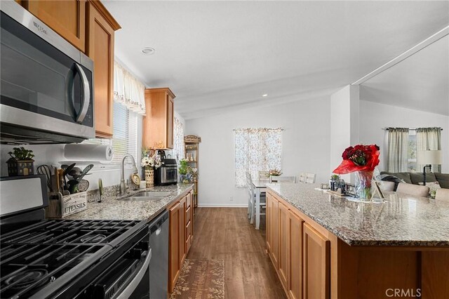 1863 Norwood Dr, Paradise, CA 95969 - kitchen with stainless steel appliances, vaulted ceiling, dark wood-style flooring, brown cabinets, and a sink
