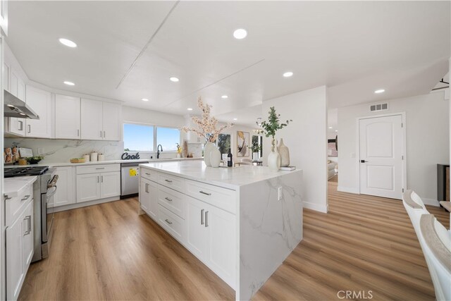 17585 Candela Dr, Rowland Heights, CA 91748 - kitchen featuring stainless steel appliances, a center island, white cabinetry, a sink, and light wood-style flooring