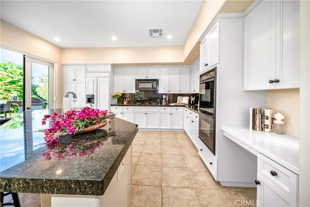 79980 Merion Ln, Quinta, CA 92253 - kitchen with black microwave, double wall oven, white cabinets, light tile patterned floors, and paneled refrigerator