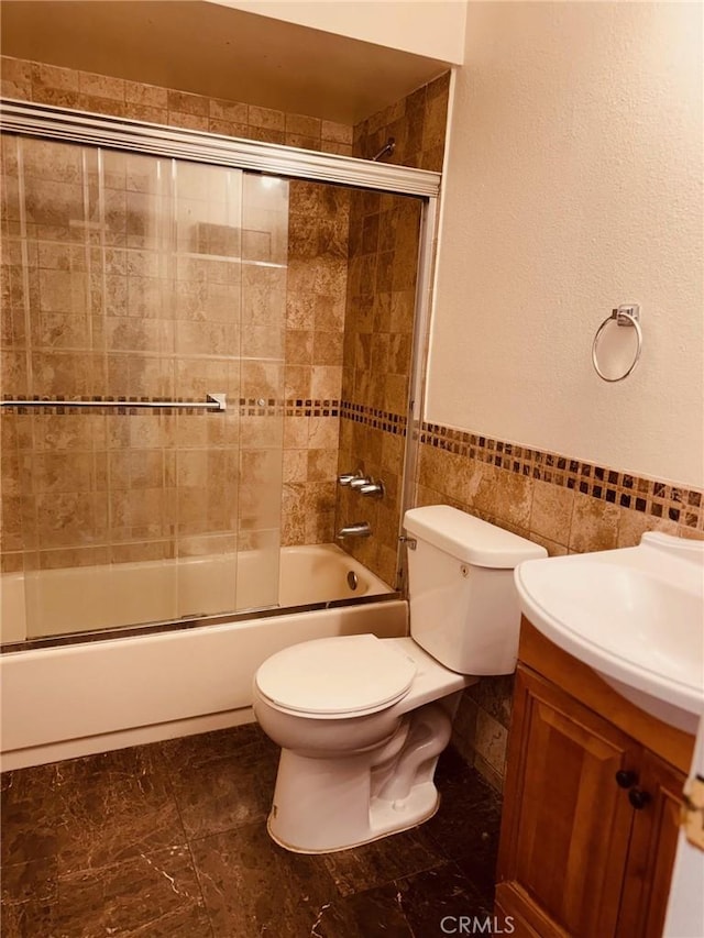 20930 Parthenia St Unit 109, Canoga Park, CA 91304 - bathroom with tile walls, toilet, enclosed tub / shower combo, vanity, and a wainscoted wall