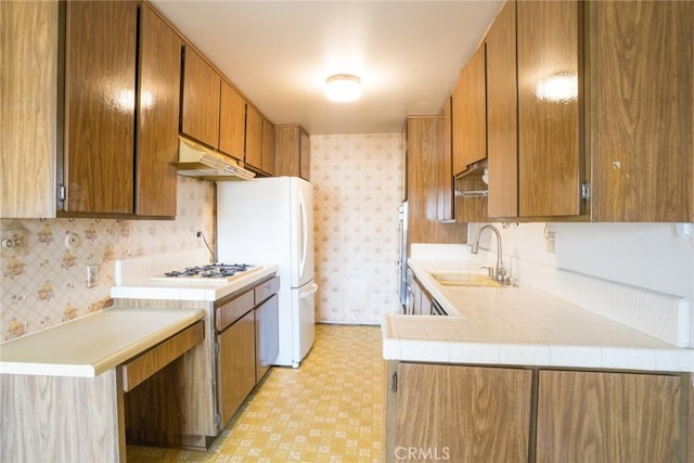 2468 Mohawk St Unit 102, Pasadena, CA 91107 - kitchen with wallpapered walls, a sink, under cabinet range hood, light countertops, and brown cabinetry