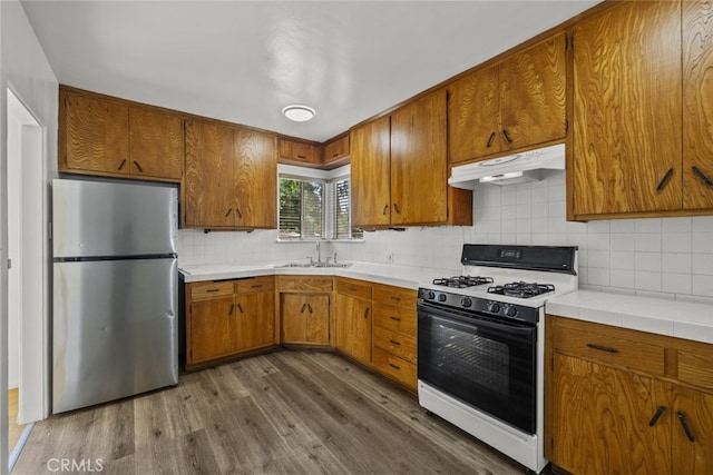 6031 Beck Ave, North Hollywood, CA 91606 - kitchen with freestanding refrigerator, range with gas stovetop, under cabinet range hood, a sink, and dark wood-style flooring