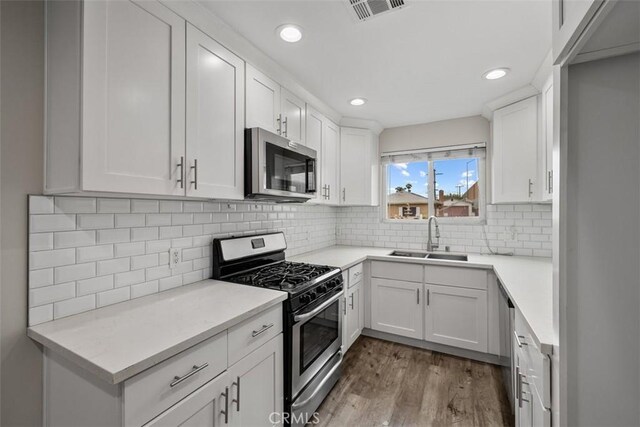 13339 Bonanza St, Arleta, CA 91331 - kitchen featuring stainless steel appliances, a sink, dark wood-style floors, white cabinetry, and recessed lighting