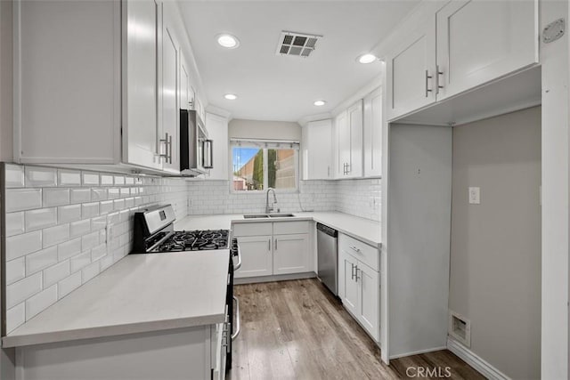 13339 Bonanza St, Arleta, CA 91331 - kitchen featuring appliances with stainless steel finishes, a sink, recessed lighting, light wood-type flooring, and white cabinetry