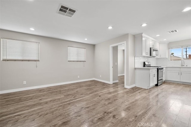 13339 Bonanza St, Arleta, CA 91331 - kitchen featuring stainless steel appliances, light wood finished floors, baseboards, backsplash, and a sink