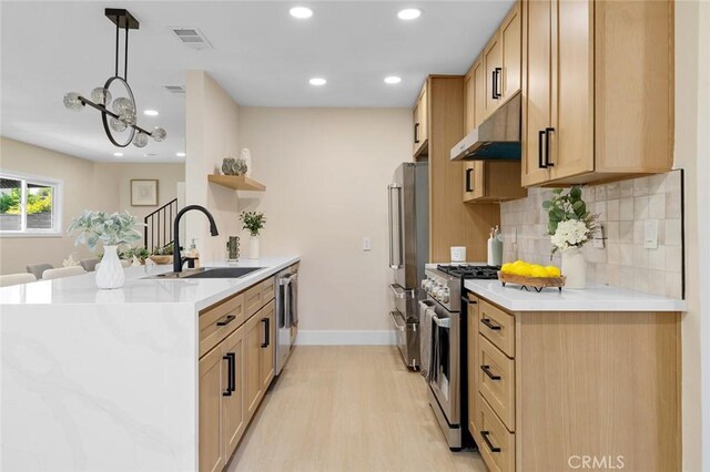 11091 Ranger Dr, Los Alamitos, CA 90720 - kitchen with a sink, appliances with stainless steel finishes, under cabinet range hood, a peninsula, and light wood-style flooring