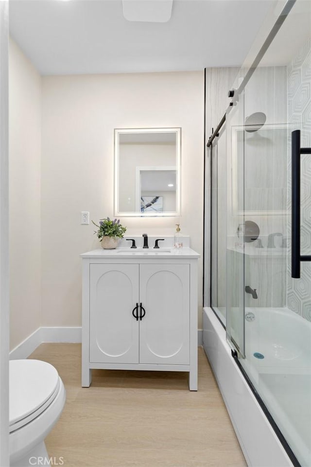 11091 Ranger Dr, Los Alamitos, CA 90720 - full bath featuring wood finished floors, toilet, vanity, shower / bath combination with glass door, and baseboards