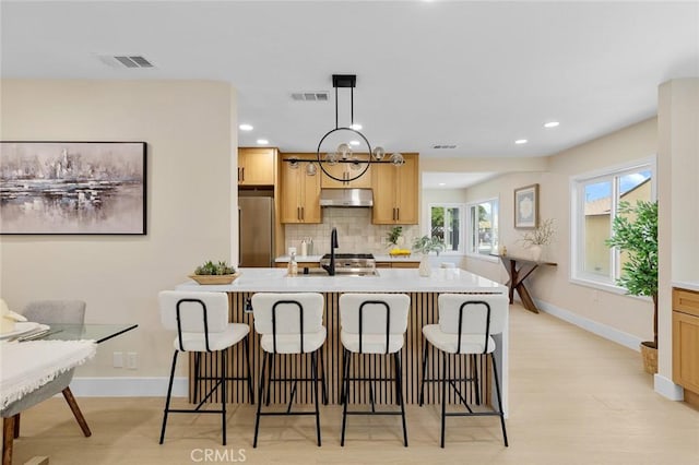 11091 Ranger Dr, Los Alamitos, CA 90720 - kitchen featuring stainless steel fridge, under cabinet range hood, tasteful backsplash, baseboards, and light countertops