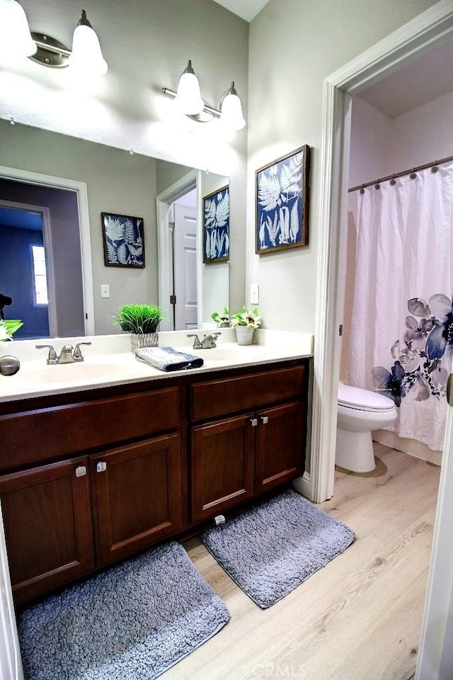 691 Pinot Blanc Ct, Los Banos, CA 93635 - bathroom featuring wood finished floors, double vanity, toilet, and curtained shower