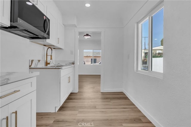 3140 Pluma St, Lynwood, CA 90262 - kitchen featuring stainless steel microwave, white cabinetry, light wood-style floors, recessed lighting, and light stone countertops