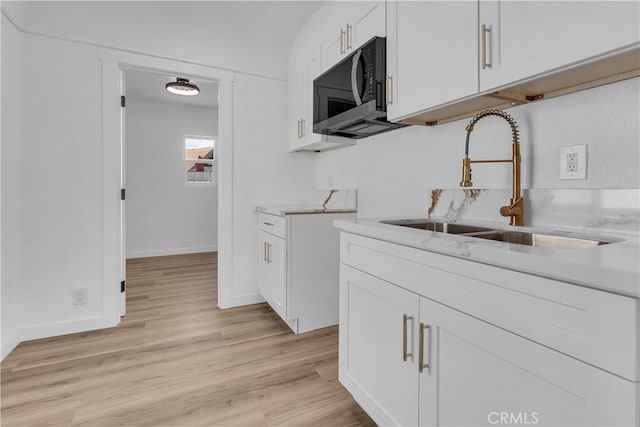 3140 Pluma St, Lynwood, CA 90262 - kitchen with black microwave, light wood-style floors, light countertops, and white cabinets