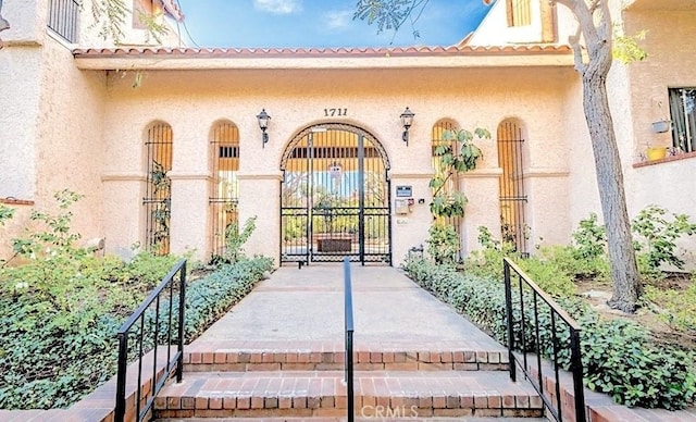 1711 Grismer Ave Unit 40, Burbank, CA 91504 - doorway to property featuring stucco siding, a gate, and a tiled roof