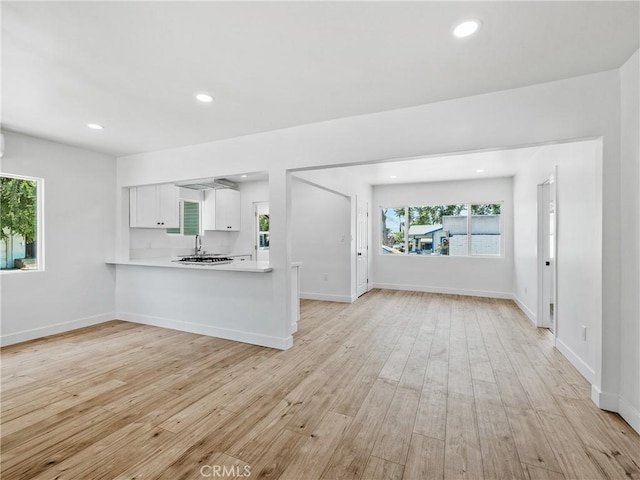 257 W 11th St, San Bernardino, CA 92410 - kitchen featuring light countertops, white cabinets, light wood-type flooring, open floor plan, and recessed lighting