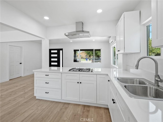 257 W 11th St, San Bernardino, CA 92410 - kitchen featuring a sink, island exhaust hood, stainless steel gas stovetop, a wall mounted air conditioner, and light wood-style flooring
