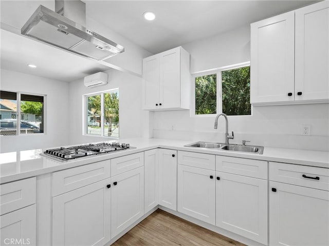 257 W 11th St, San Bernardino, CA 92410 - kitchen featuring a sink, stainless steel gas cooktop, an AC wall unit, wall chimney exhaust hood, and light countertops