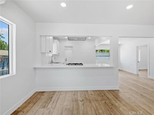 257 W 11th St, San Bernardino, CA 92410 - kitchen featuring a sink, light countertops, light wood-style flooring, baseboards, and white cabinets