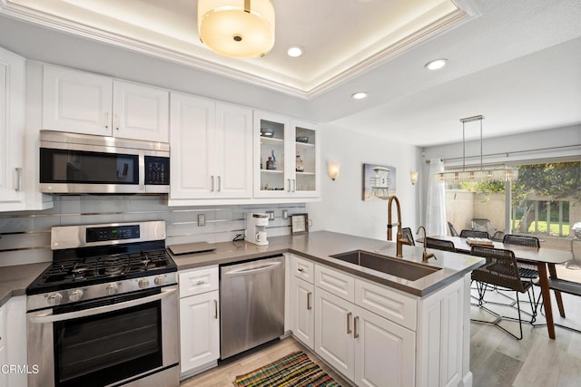 3125 Harbor Blvd, Oxnard, CA 93035 - kitchen with stainless steel appliances, a peninsula, a raised ceiling, backsplash, and light wood-style flooring