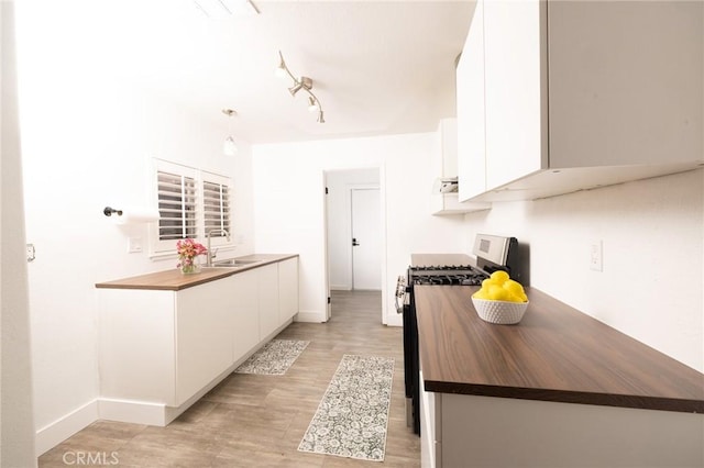 5760 Falling Leaf Ln, Jurupa Valley, CA 92509 - kitchen featuring stainless steel range with gas cooktop, wood counters, white cabinets, and track lighting