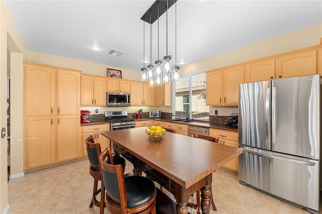 65565 Acoma Ave Unit 1, Desert Hot Springs, CA 92240 - kitchen featuring appliances with stainless steel finishes, light brown cabinetry, dark countertops, light tile patterned floors, and hanging light fixtures
