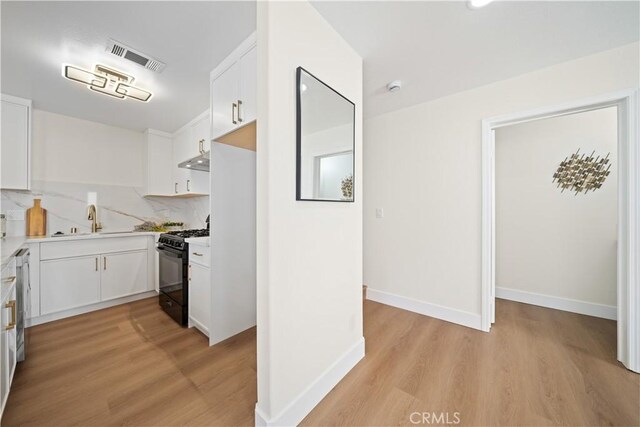 4431 W 138th St Unit B, Hawthorne, CA 90250 - kitchen featuring black gas range, under cabinet range hood, a sink, light wood finished floors, and white cabinetry