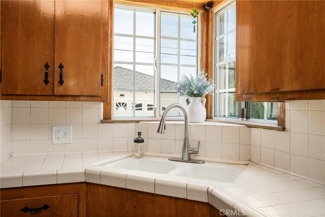 4660 Whitney Dr, El Monte, CA 91731 - kitchen featuring a sink, plenty of natural light, brown cabinetry, and tasteful backsplash