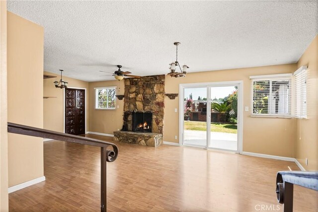 4660 Whitney Dr, El Monte, CA 91731 - unfurnished living room with a textured ceiling, wood finished floors, a ceiling fan, baseboards, and a stone fireplace