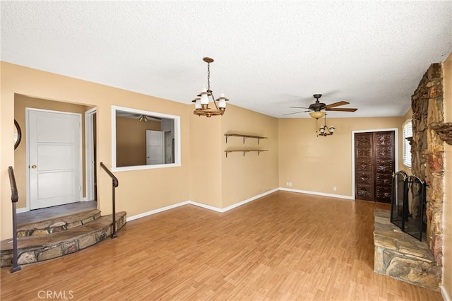 4660 Whitney Dr, El Monte, CA 91731 - unfurnished living room featuring a textured ceiling, wood finished floors, baseboards, a ceiling fan, and a stone fireplace