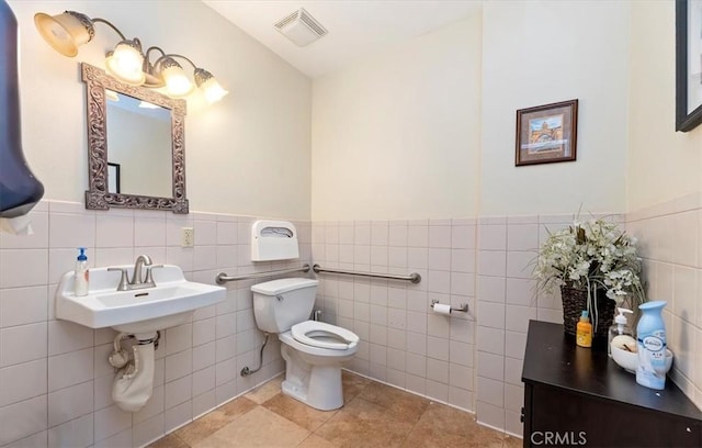 3845 10th St, Riverside, CA 92501 - bathroom with toilet, tile walls, a wainscoted wall, tile patterned floors, and a sink