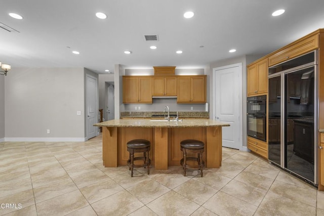 1315 Donegal Way, Oxnard, CA 93035 - kitchen featuring paneled refrigerator, light tile patterned floors, light stone counters, an island with sink, and recessed lighting