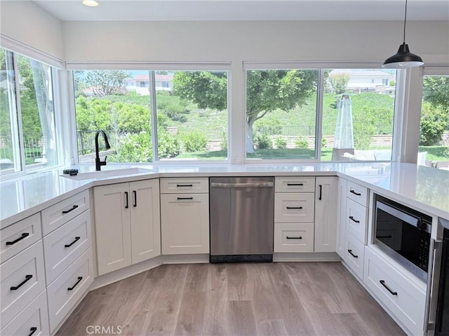26871 Recodo Ln, Mission Viejo, CA 92691 - kitchen with stainless steel appliances, a sink, light countertops, light wood-style floors, and white cabinetry