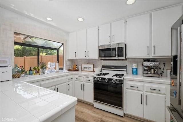 1132 Santiago Dr Unit 11, Placentia, CA 92870 - kitchen with white gas stove, stainless steel microwave, tile counters, white cabinets, and recessed lighting