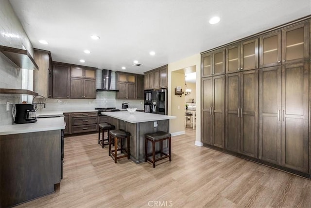 19454 Copper Ridge St, Perris, CA 92570 - kitchen featuring wall chimney exhaust hood, refrigerator with ice dispenser, light wood-type flooring, a breakfast bar area, and a center island